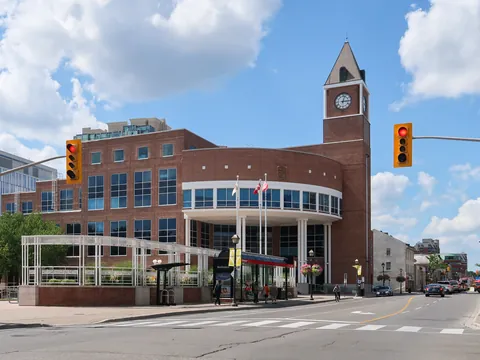 Brampton City Hall's red-brick rotunda and clock tower in downtown Brampton on a sunny summer day, with Main Street and a blue sky with white clouds